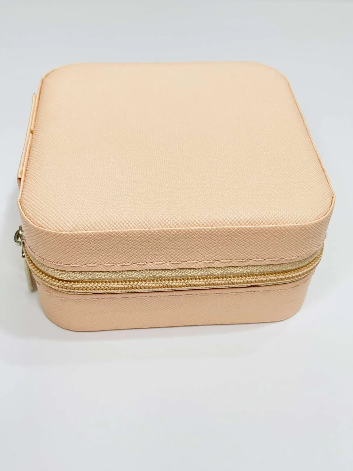 Beige jewellery box with a gold zipper on a light gray background